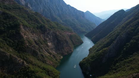 touring boats sailing through a stunning river valley surrounded by majestic mountains in the alps of albania