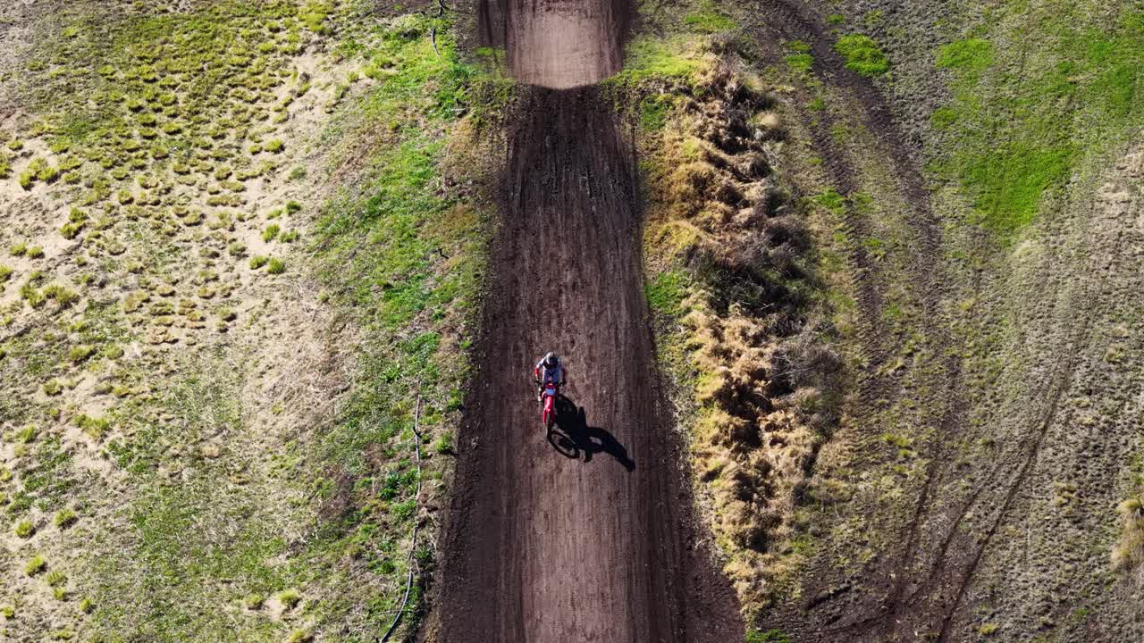 Motorcyclist rides along dirt trail, overhead drone shot, bright daylight, rural Australian landscape