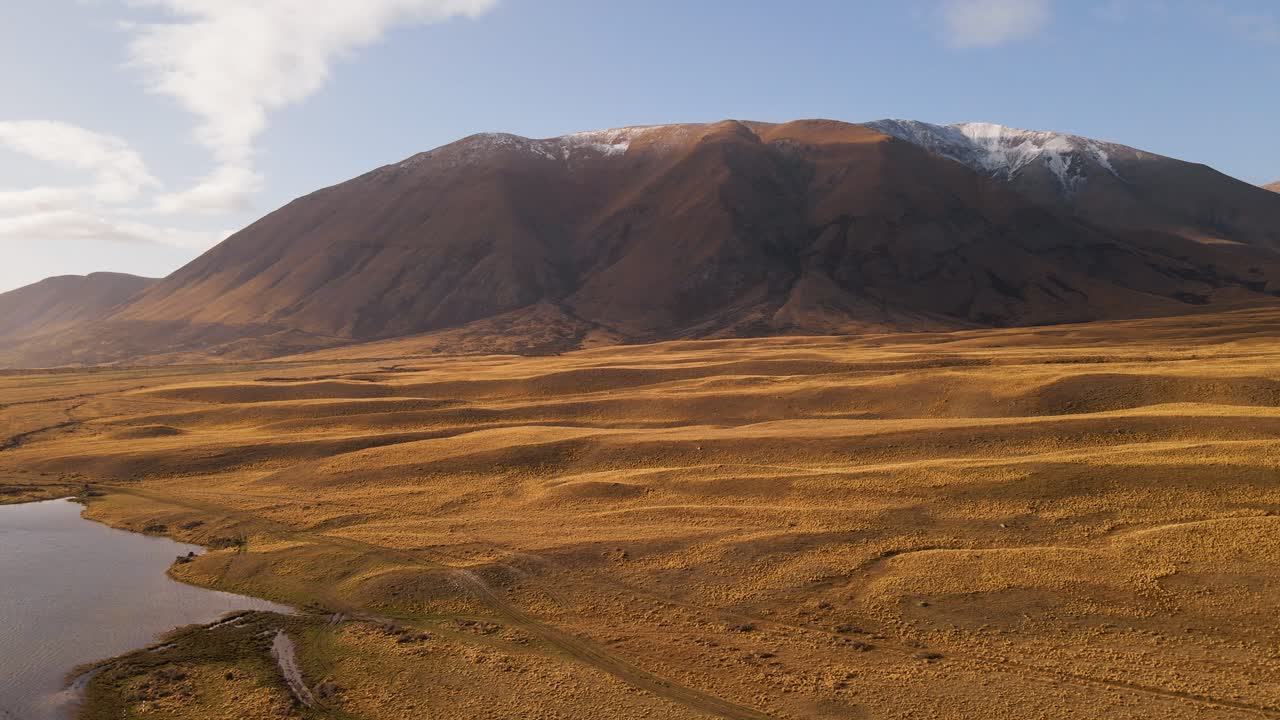 carro aéreo a la izquierda de hermosas llanuras onduladas junto con montañas que rodean el borde de un pequeño lago
