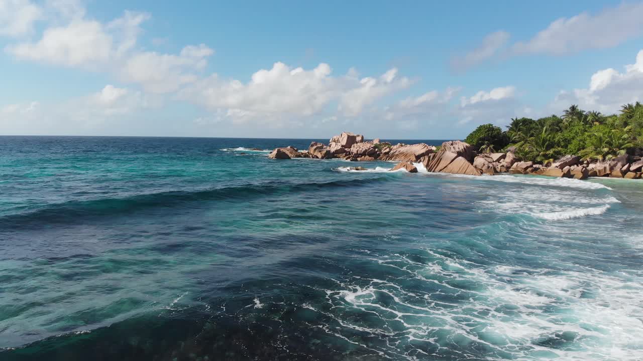 Vista aerea che segue le onde che si infrangono sulle spiagge bianche e deserte ad Anse Coco, Petit Anse e Grand Anse a La Digue, un'isola delle Seychelles.