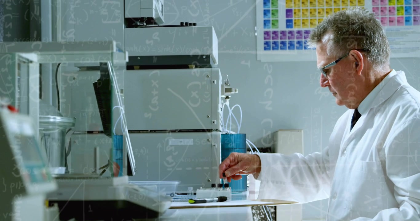 Senior male scientist picking up and checking vial on bench, operating lab instruments for analysis