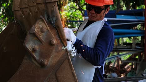 hombres profesionales que usan gafas de protección y guantes de construcción trabajan en el taller de casa con un molinillo angular. el metal de lijado hace chispas, primer plano