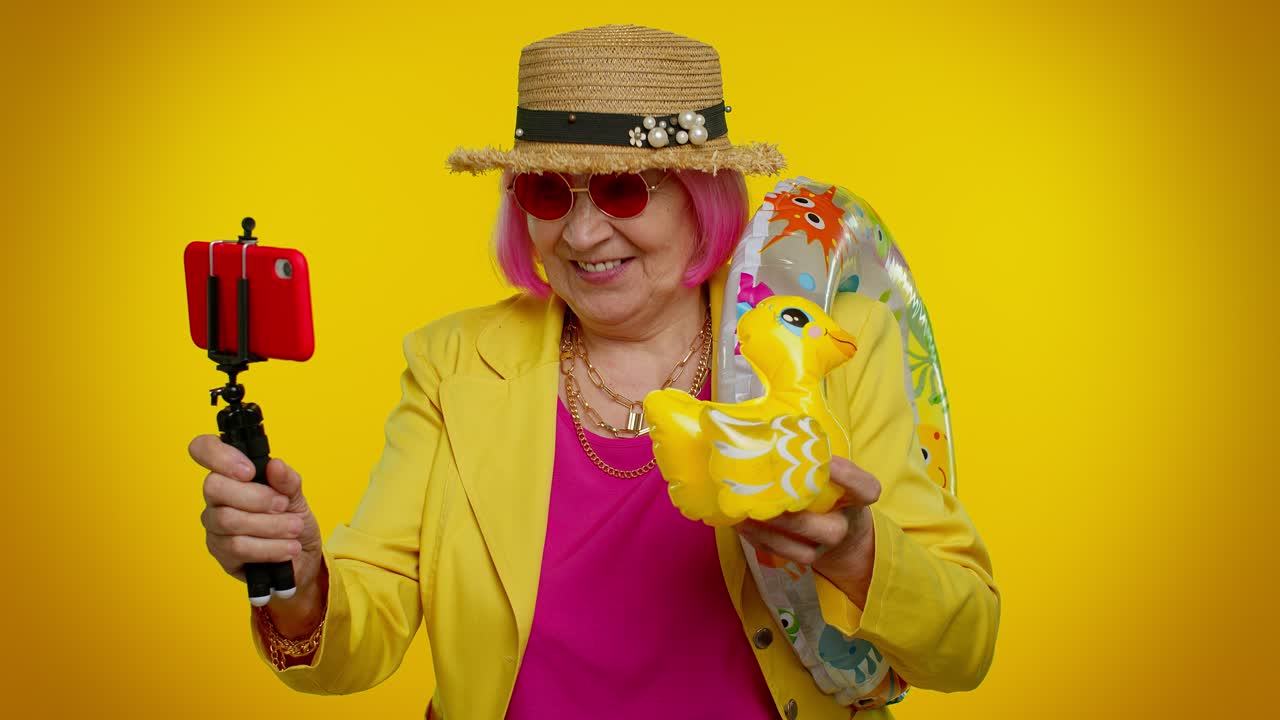 una mujer mayor feliz tomando una selfie con un flotador de pato