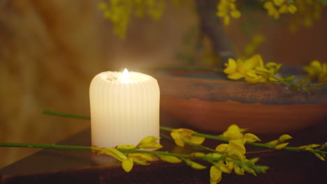 Soothing-white-candle,-yellow-flowers-with-rustic-decoration-and-natural-stone-wall