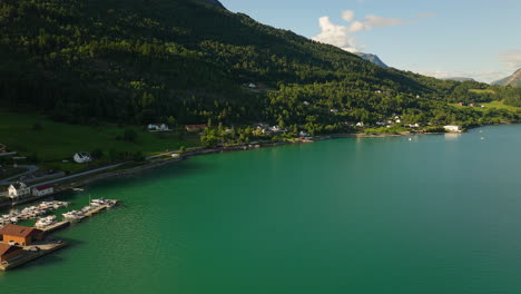 las brillantes aguas verdes y azules del fiordo de lustra mientras la luz del sol ilumina la ladera boscosa