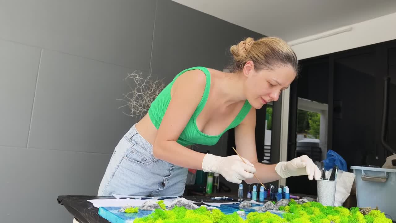 mujer creando arte de resina con musgo y montañas