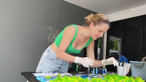 woman creating resin art with moss and mountains