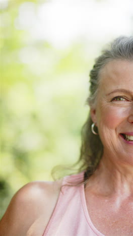 vertical video: smiling senior woman outdoors, enjoying sunny day in casual attire