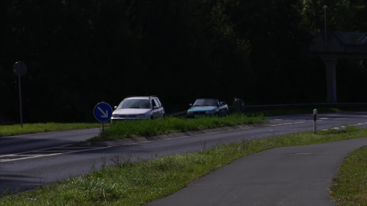The exterior wall of an old house in Goldbach, Germany, near a bicycle path and a busy road with car traffic. A blend of historic architecture, modern transportation, and daily urban life.