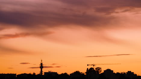 silueta de la grúa de construcción y la antena de telecomunicaciones con naranja al atardecer