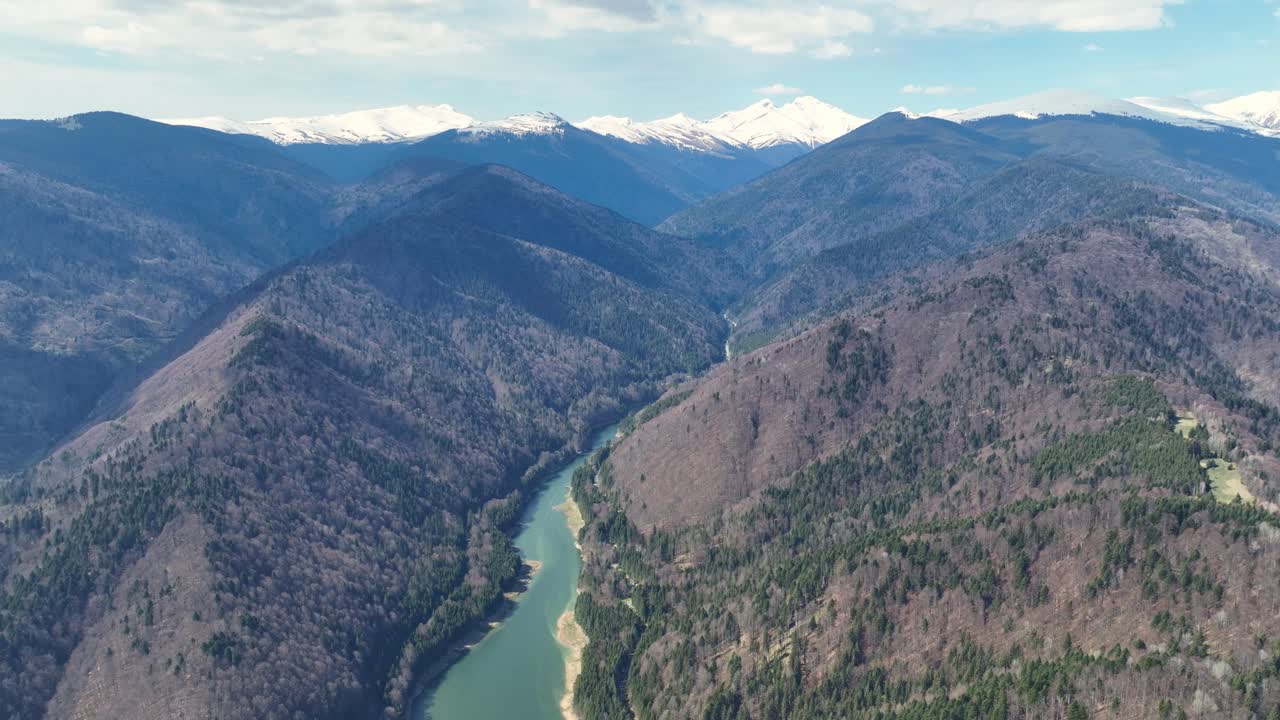 Aerial View of a Mountain River Valley with Snow-capped Peaks