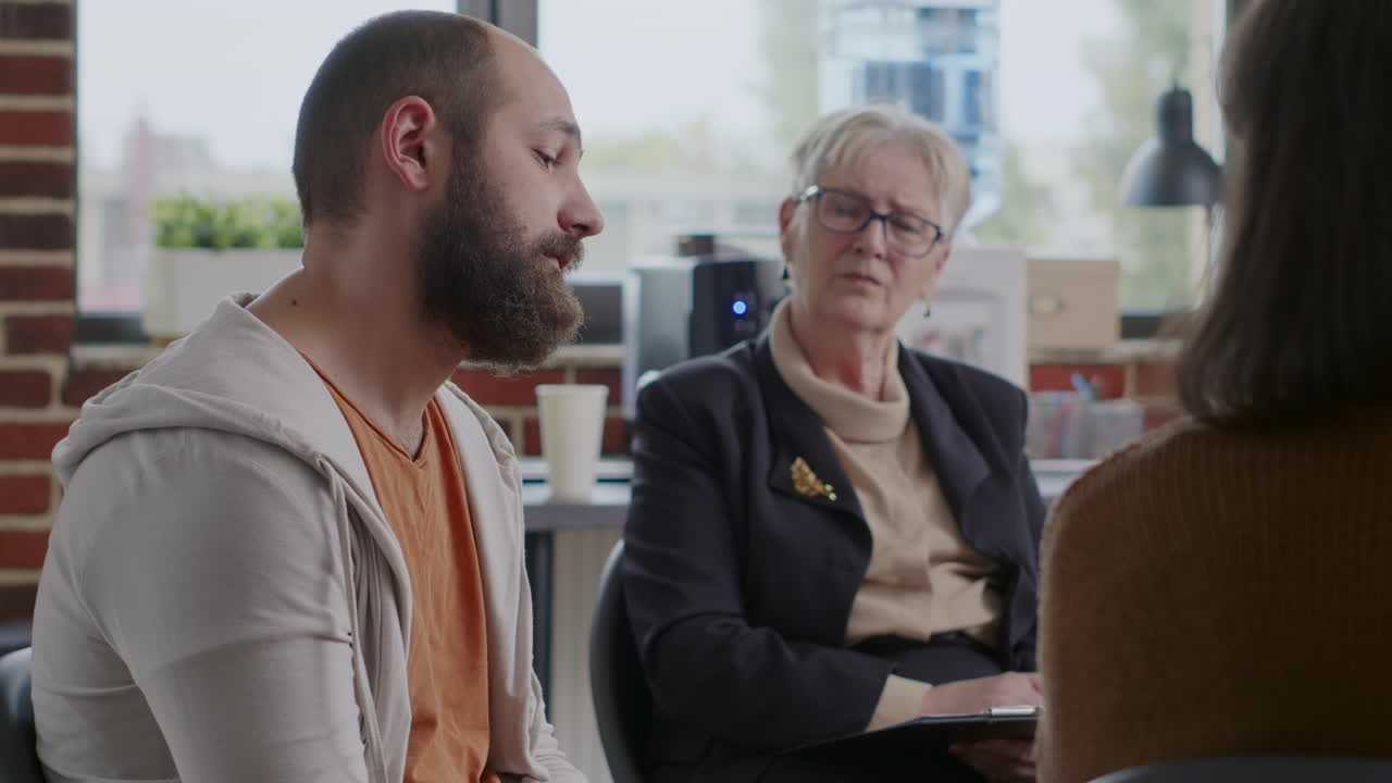 Man in despair sharing sad story about alcohol addiction in front of people at aa group therapy