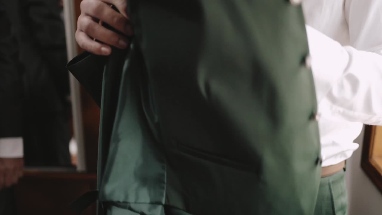 셔츠와 녹색 타이를 입은 남자가 녹색 재을 들고 공식적인 행사를 준비하고 있다