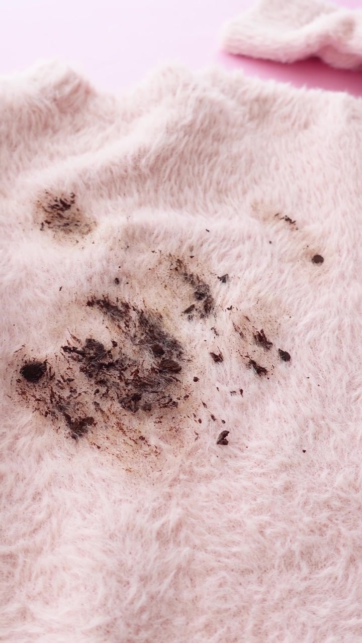 Macchia scura su tessuto morbido e peloso rosa tenue.