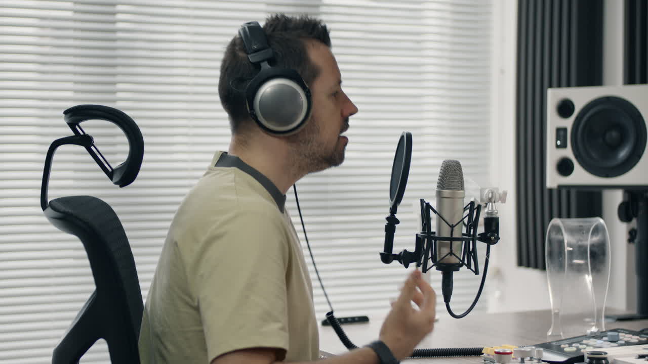 Singing into a microphone in a studio setup, with a man using headphones and gesturing expressively