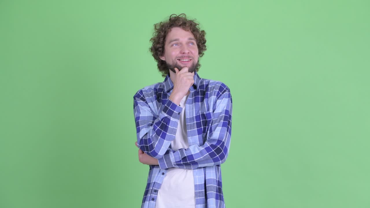 un joven guapo, barbudo y hipster con el cabello rizado.