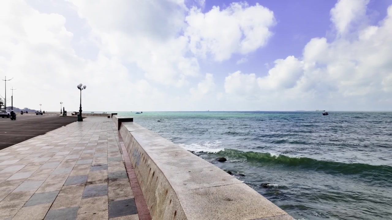 Orang-orang dapat menikmati pemandangan laut dan langit di Bai Truoc, Vung Tau, Vietnam. Perahu-perahu terlihat di atas air. Ombak bergerak lembut di bawah langit yang cerah.