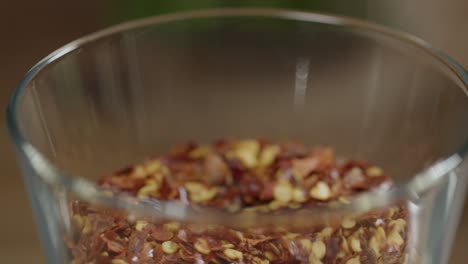 spoon stirs ground dried chili pepper in a small glass container, essential ingredient for the preparation of argentine chimichurri