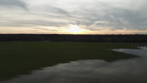 Sunset-over-Loosahatchie-Park,-TN-with-calm-water-and-expansive-green-fields,-serene-evening-mood,-aerial-shot