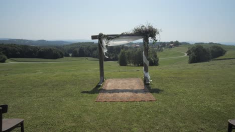 outdoor wedding setting with chairs, arch and carpet on field, wide dolly forward