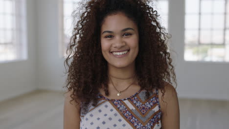 Lindo-Retrato-De-Mujer-Joven-De-Una-Chica-Bastante-Mestiza-Sonriendo-Posando-Para-La-Cámara-Alegre-Cabello-Rizado-Femenino-Positivo-En-El-Fondo-Del-Apartamento