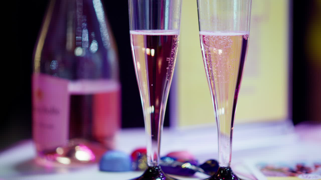 Two glasses of champagne with a rose bottle on the background