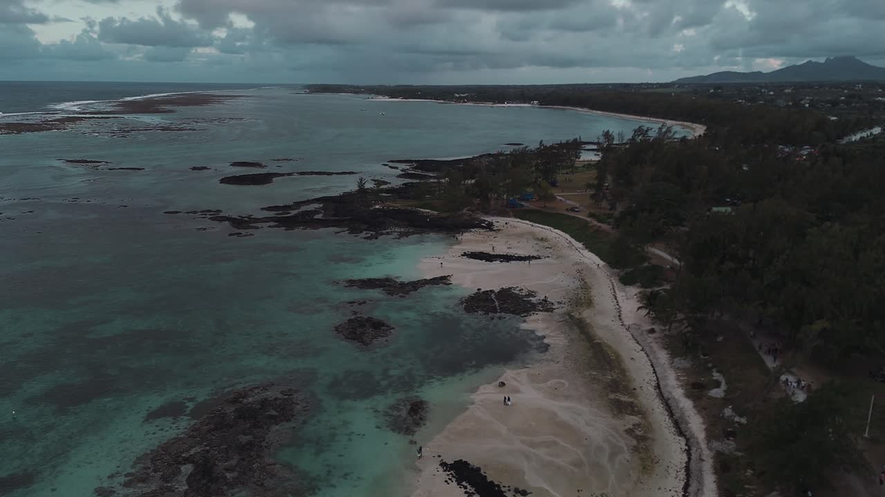 Filmato aereo con drone della spiaggia di Belle Mare con la bassa marea a Mauritius, che rivela lagune turchesi, formazioni coralline e il paesaggio della costa tropicale dall'alto