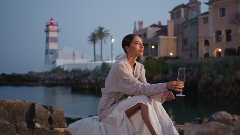 mujer disfrutando del vino junto al mar al atardecer