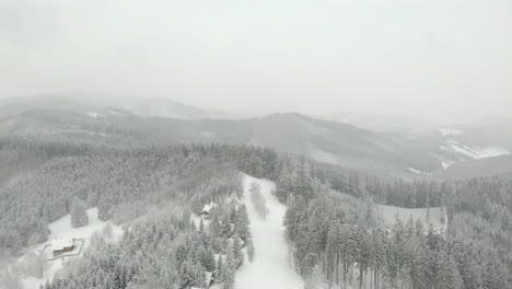 Aerial-view-over-Czech-mountains,-on-grey,-snowy-winter-day-in-Kohutka
