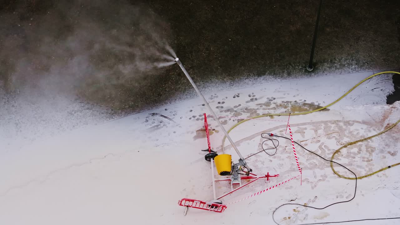 Snow machine sprays fine mist, drone orbits in wintery Victory Park Riga Latvia