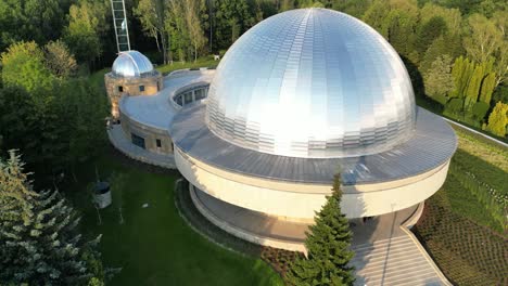 Majestic-stars-observatory-during-a-beautiful-summer-day,-surrounded-by-lush-greenery,-grass,-and-trees-under-a-clear-blue-sky