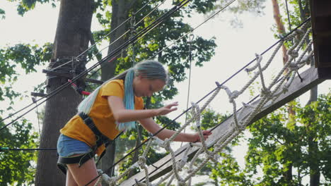 a child climbs ropes high in the trees - having fun in a rope city in an amusement park