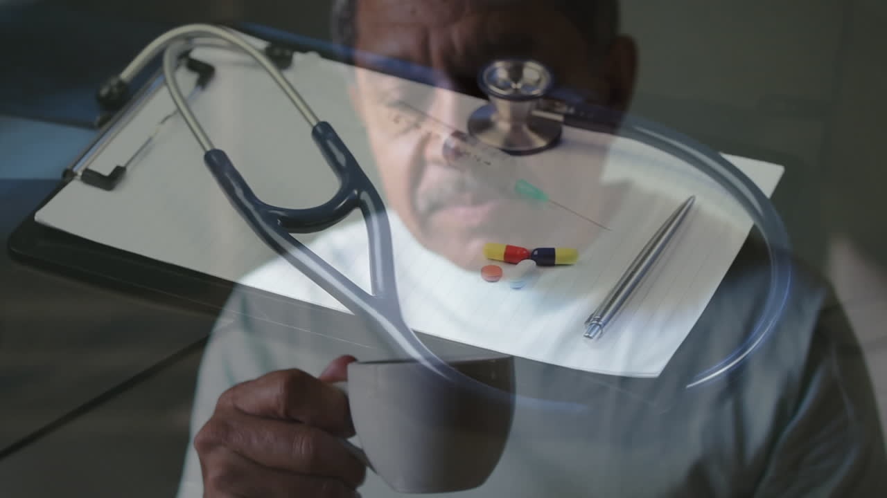 Ronddraaiende stethoscoop en injectiespuit tegen Afro-Amerikaanse senior man die thuis koffie drinkt