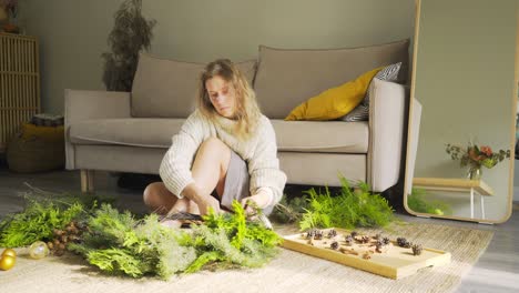 woman makes xmas wreath in interior