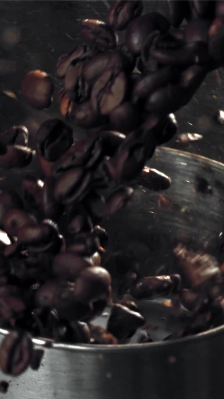 Chicchi di caffè tostati freschi che cadono in un macinacaffè al rallentatore