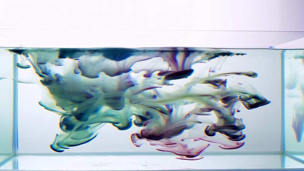 Multiple colored ink plumes descend into clear water inside rectangular glass tank, spreading into ribbon curls, soft fans, and layered chromatic flow with gentle backlight, creating fluid abstract