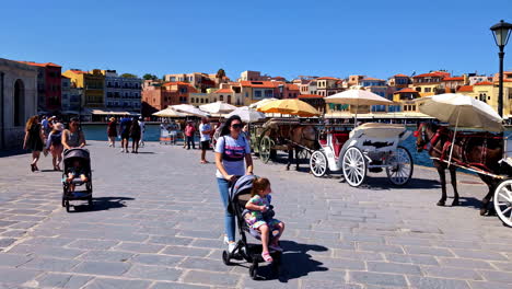 chania, crete, greece - tourists strolling around the venetian harbor with the lighthouse in the background - panning shot