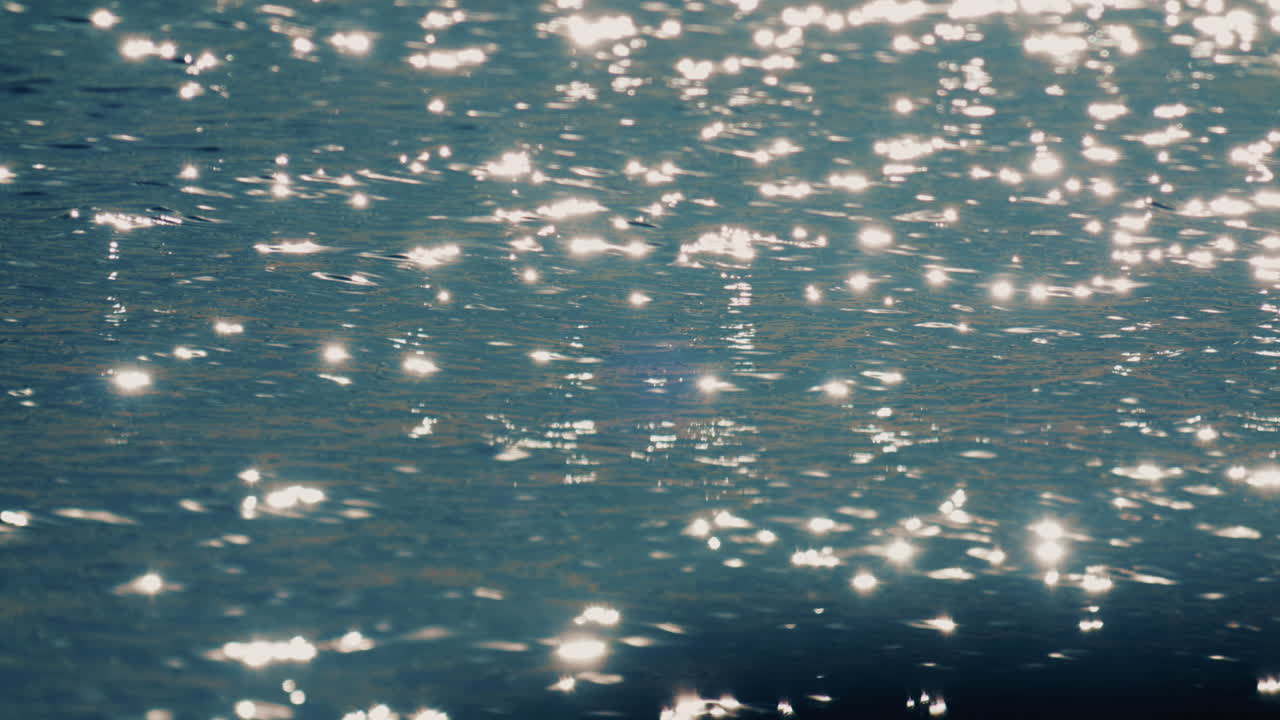 穏やかに揺れる海水に太陽光が反射してきらめく様子をクローズアップで捉えた映像