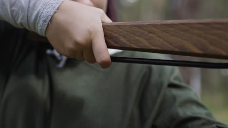 girl in old styled clothes presses trigger of crossbow