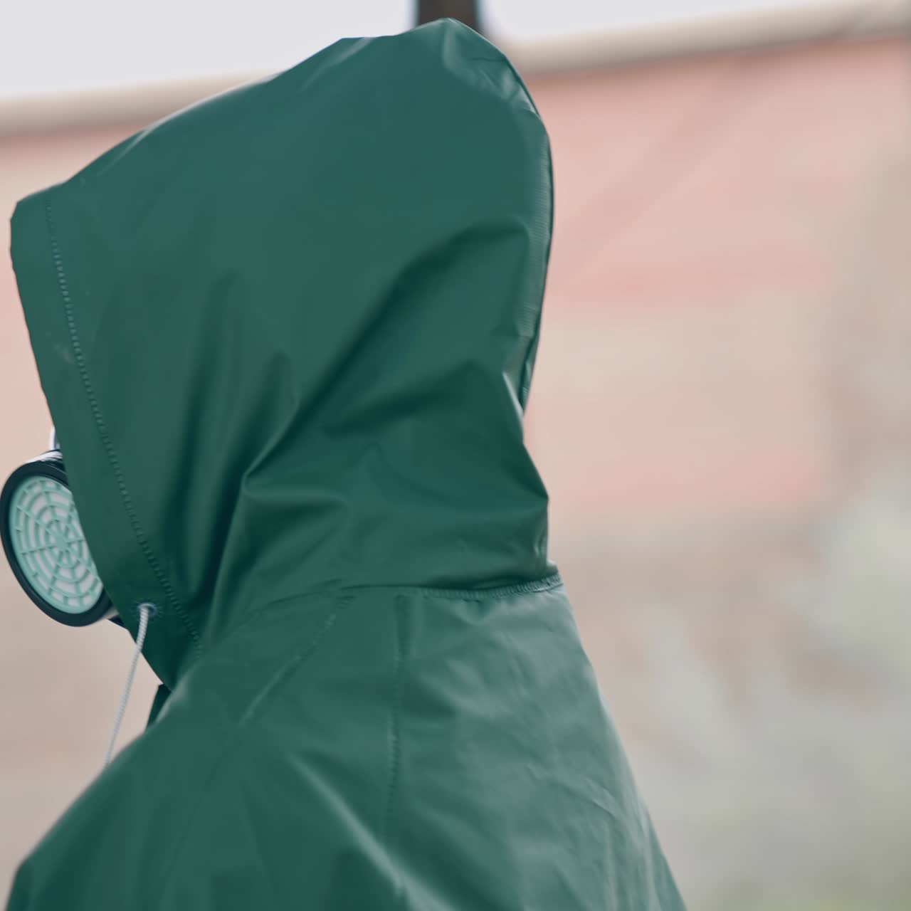 Person in chemical protective suit standing in distracted place. Survivor in abandoned place with piles of garbage from ruined buildings. Apocalypse concept