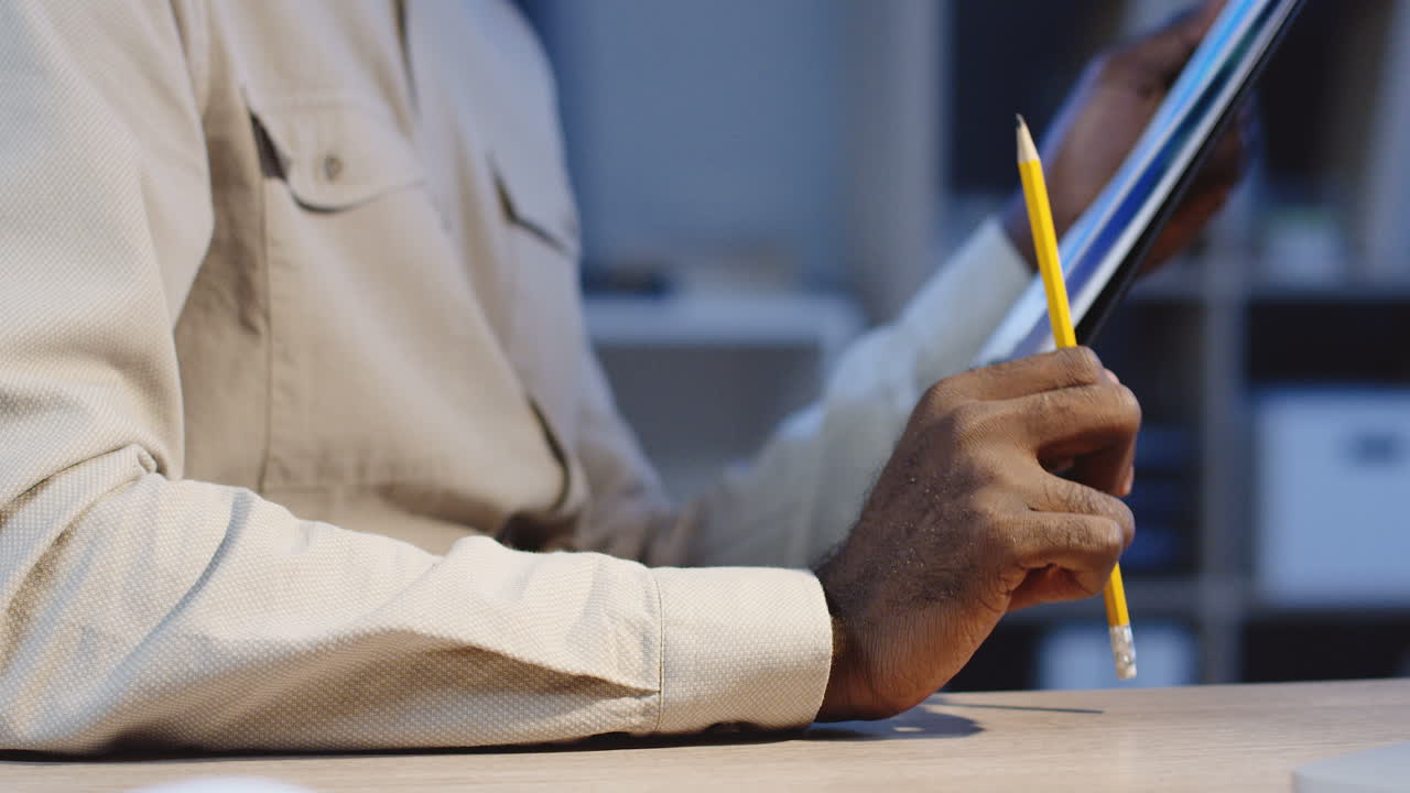 Close Up View Of Young Office Worker Holding A Pencil And Documents, Thinking About His Project And Making Notes There