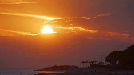 Puesta-De-Sol-En-Croacia-Sol-Cayendo-Al-Mar-Sobre-Un-Cielo-Rojo-Anaranjado-Silueta-De-Sombrillas