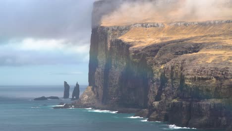 Vista-Panorámica-Del-Hermoso-Arco-Iris-Que-Brilla-Frente-A-La-Costa-Masiva-Y-Las-Pilas-De-Mar-Risin-Og-Kellingin,-En-El-Fondo-De-La-Isla-Streymoy,-Islas-Feroe