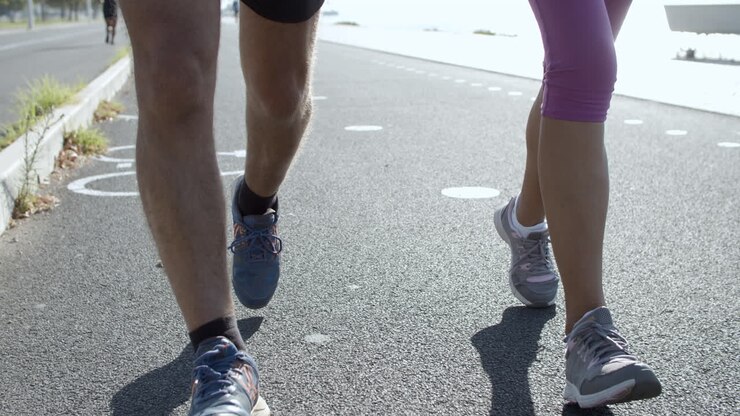 Gambe maschili e femminili che corrono su strada asfaltata