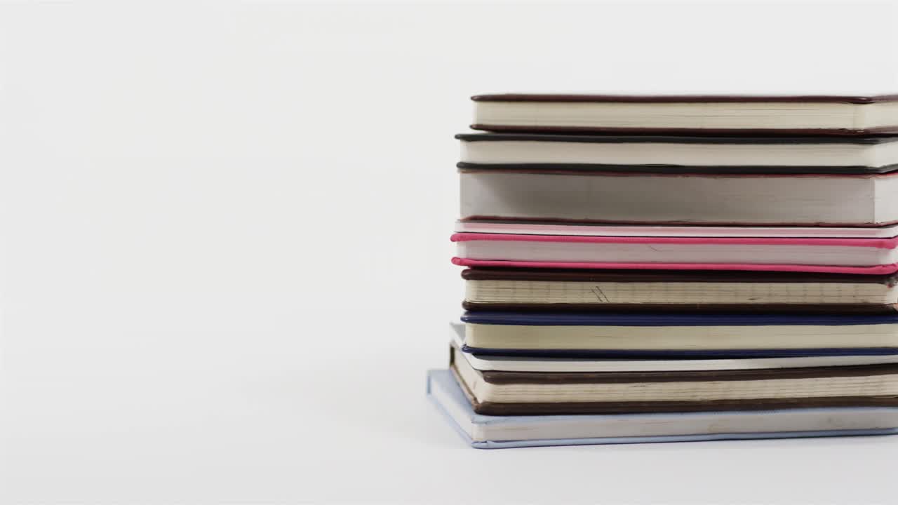 Close up of stack of books on white background, in slow motion