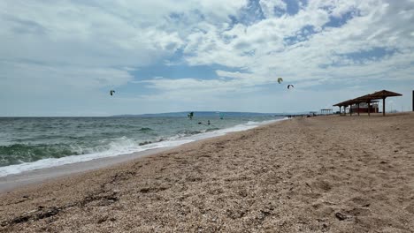 a beautiful view of a beach in russia with kitesurfers enjoying the sunny weather and gentle waves