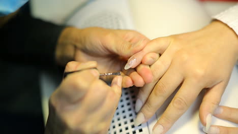 woman in salon receiving manicure by nail beautician