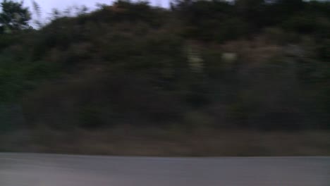 a car travels along pacific coast highway in early morning or late evening as seen through the side window