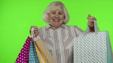 Senior-grandma-raising-shopping-bags,-celebrating,-satisfied-with-purchase,-discount.-Chroma-key