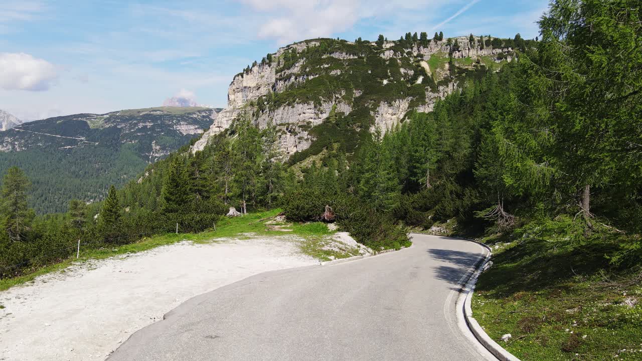 Bikepacking cyclist navigates winding road downhill in rugged Dolomite mountains